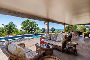 A covered outdoor area with a pool, wicker furniture, and a view of the ocean. - *NEW LISTING Sunset Views, Pool and Spacious Modern Comfort Getaway!! (Waimea,)