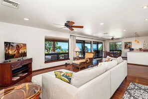 A spacious living room with a large sofa, a television, and a dining area with a view of the ocean. - *NEW LISTING Sunset Views, Pool and Spacious Modern Comfort Getaway!! (Waimea,)