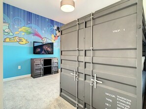 A room with a large grey storage unit labeled 'YRCP 1' and a wall decorated with cartoon characters and fireworks.