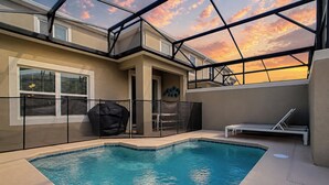 A swimming pool with a glass ceiling, surrounded by a covered patio area with seating.