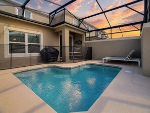 A swimming pool with a glass ceiling, surrounded by a covered patio area with seating.