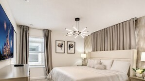 A hotel room with a large bed, a bedside table, a lamp, and a wall-mounted TV.