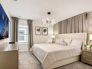 A hotel room with a large bed, a bedside table, a lamp, and a wall-mounted TV.