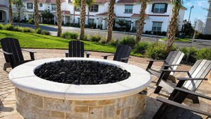 A circular stone fire pit surrounded by Adirondack chairs in an outdoor setting.