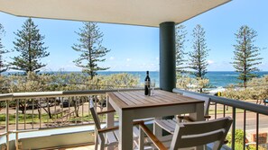 A balcony with a table, chairs, and a bottle of wine. - Seapoint Unit 14, 32 Victoria Tce, Kings Beach (Kings Beach)