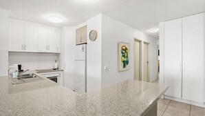 Una cocina moderna con armarios blancos, encimera de granito, horno empotrado y refrigerador.