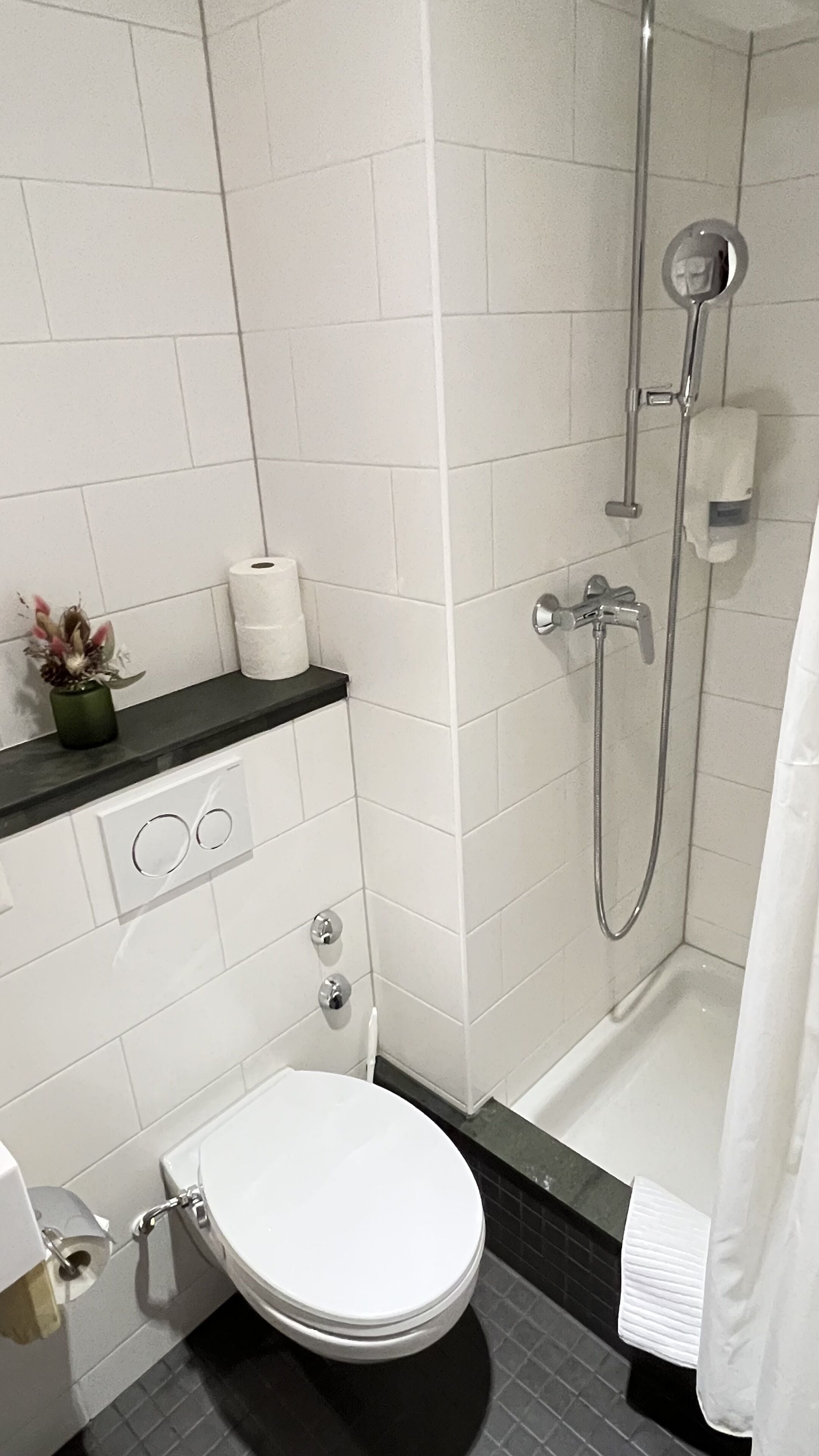 Et moderne badeværelse med toilet, vask og brusebad.