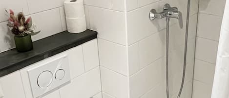 Et moderne badeværelse med toilet, vask og brusebad.