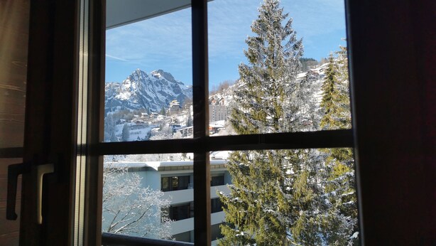 A window view of a snowy mountain landscape with buildings and trees.