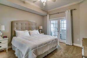 A bedroom with a large bed, two bedside tables with lamps, a ceiling fan, and a sliding glass door leading to a balcony. - Gulf Front - 3BR 4BA - Lazy River - The Oasis at Orange Beach (Orange Beach)
