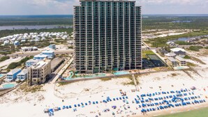 A high-rise hotel with multiple floors, a beach area with umbrellas, and a water park. - Gulf Front - 3BR 4BA - Lazy River - The Oasis at Orange Beach (Orange Beach)