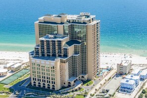 Un hôtel de grande hauteur, avec de nombreux étages, une vue sur la plage et un espace piscine.