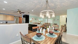 A dining area with a wooden table set for four, surrounded by chairs. - Salty Sea Life - Canal Pool Home-Just 5 Min to Anna Maria Island - By Island Rea (Bradenton)
