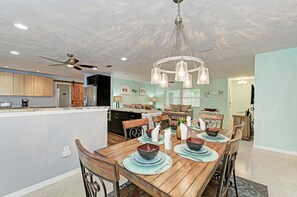 A dining area with a wooden table set for four, surrounded by chairs.
