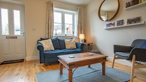 A cozy living room with a blue sofa, a wooden coffee table, and a grey armchair. - Modern and bright 2-bed home near Ludlow centre - Pass the Keys (Ludlow)