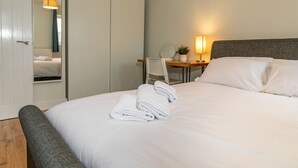 A hotel room with a neatly made bed, a desk with a chair, a lamp, and a mirror. - Modern and bright 2-bed home near Ludlow centre - Pass the Keys (Ludlow)