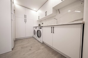 A laundry room with a washing machine, cabinets, and a marble countertop.