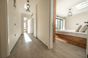 Een hotelkamer met een houten bed, een raam met uitzicht en een gang naar een andere kamer.