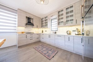 Een moderne keuken met lichte houten kastjes, een gasfornuis en een koffiezetapparaat.
