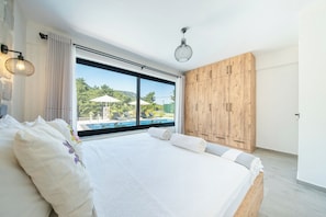 Une chambre avec un grand lit, une armoire en bois et une vue sur une piscine.