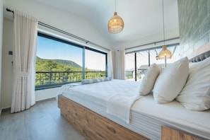 Une chambre avec un grand lit, une vue sur la verdure et un balcon.