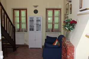 A living room with a staircase, a cabinet with glass doors, and a vase with flowers. - Loft Angela Charming Aptmnt in Pietrasanta Center (Pietrasanta)