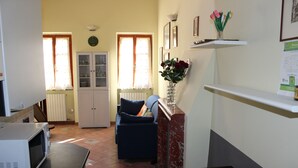A compact living space with a kitchen area, a dining table, a microwave, a cabinet, a sofa, and a vase with flowers. - Loft Angela Charming Aptmnt in Pietrasanta Center (Pietrasanta)