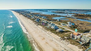 Vista aérea de un pueblo costero con una extensa playa de arena, casas y una masa de agua.