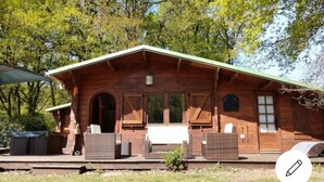 Eine Holzhütte mit Veranda, Korbmöbeln und einem kleinen Garten.