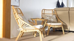 A room with two wicker chairs, a small glass table, and a beige sofa. - Soldiers Point Absolute Waterfront The Peninsula (Soldiers Point)