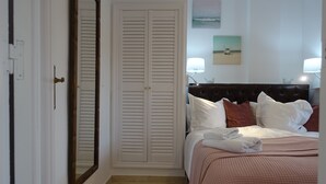 Ein Schlafzimmer mit einem Bett, einem großen Spiegel, einem Kleiderschrank und Bildern an der Wand.