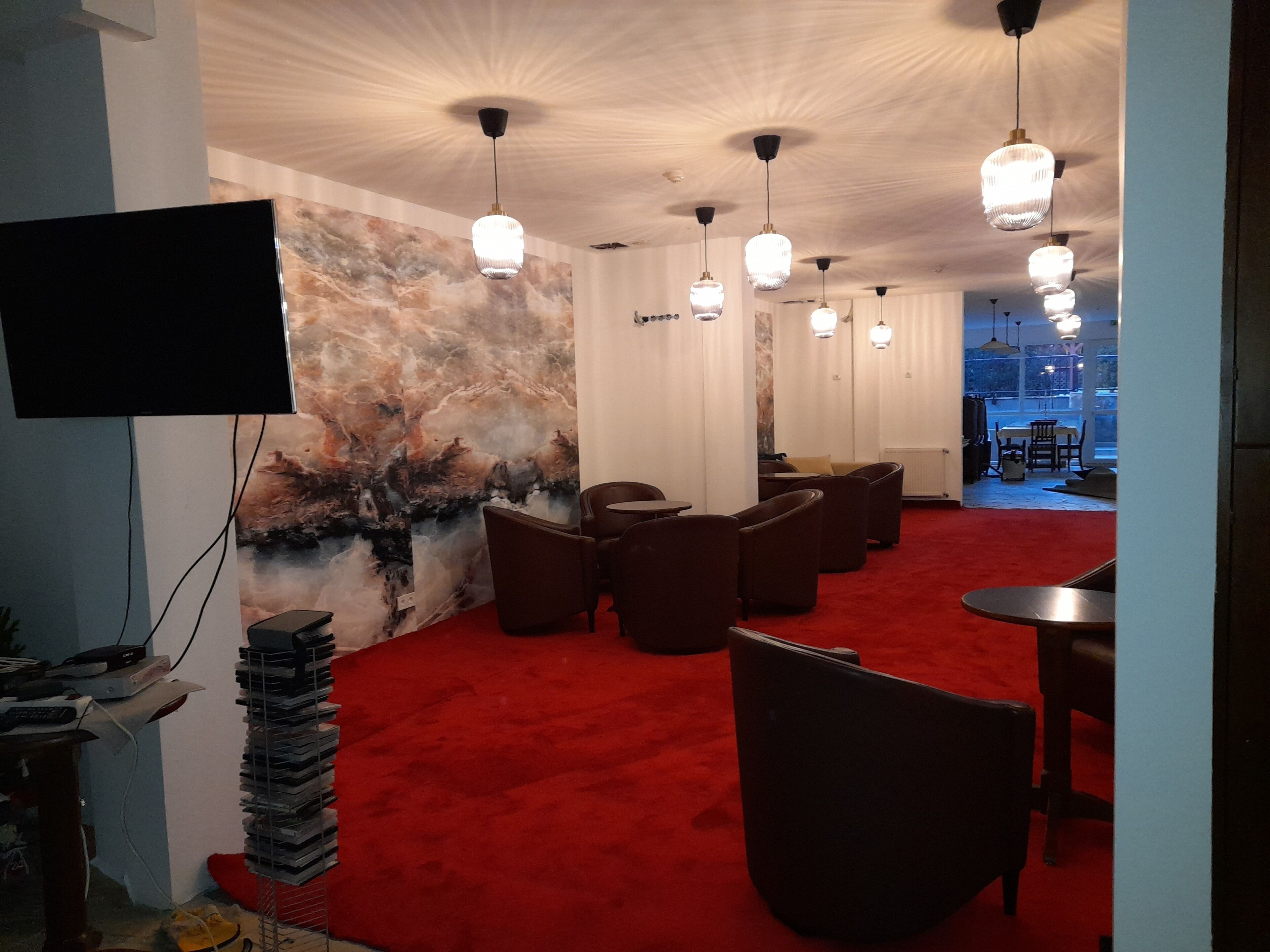 A hotel lobby with a red carpet, multiple seating areas, and a large wall mural.