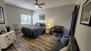 Ein Schlafzimmer mit einem Bett, einem Schreibtisch, einem Stuhl, einer Kommode und einem Fenster.