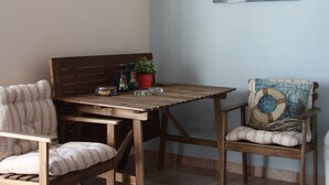 A dining area with a wooden table and chairs, a hanging light fixture, and a sailboat painting on the wall.