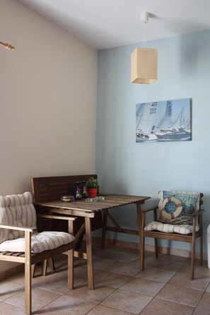 Un comedor con una mesa y sillas de madera, una lámpara colgante y un cuadro de un velero en la pared.
