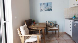 A dining area with a wooden table and chairs, a small potted plant, and a sailboat painting on the wall.