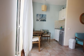 A compact kitchen with a dining area, a small sink, and a refrigerator. - Mandola Studios Beachside - Skala Beach (Blue Studio) (Skala)