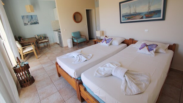 A hotel room with two beds, a desk, a chair, and a painting on the wall.