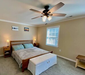 A bedroom with a bed, bedside tables, a ceiling fan, and a window.