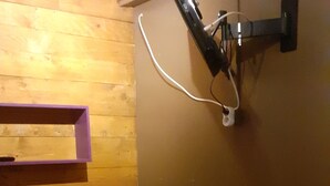 Une petite chambre avec un lit simple, un mur en bois et une lampe fixée au mur.