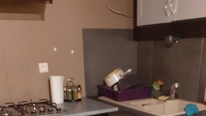 Une cuisine équipée d’une cuisinière à gaz, d’un four et d’un évier. On y trouve également des placards et un plan de travail.
