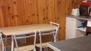 Une pièce aux murs lambrés, avec une table et des chaises, un four à micro-ondes et un réfrigérateur.