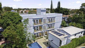 A multi-story hotel with a rooftop pool, surrounded by lush greenery.