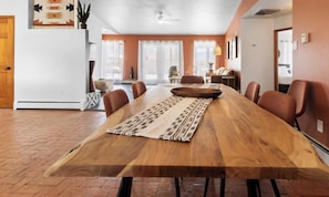 Un comedor con una larga mesa de madera, sillas y un corredor con diseño.