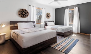 A modern bedroom with two beds, a ceiling fan, and a large window with curtains. - Rancho de Valle del Norte - An Irvie Home (Albuquerque)