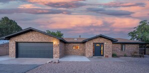 A two-story house with a brick exterior, a garage, and a front door with a small porch. - Rancho de Valle del Norte - An Irvie Home (Albuquerque)
