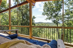 A wooden deck with a view of a forest and hills.