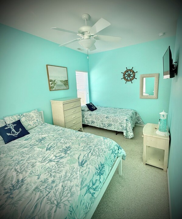 A bedroom with two beds, a ceiling fan, a dresser, a nightstand, and nautical-themed decor. - Beautiful condo in prime location! 2 blocks from boardwalk & convention center. (Wildwood)