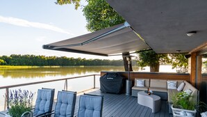 A deck with outdoor seating, a covered area, and a view of a lake.