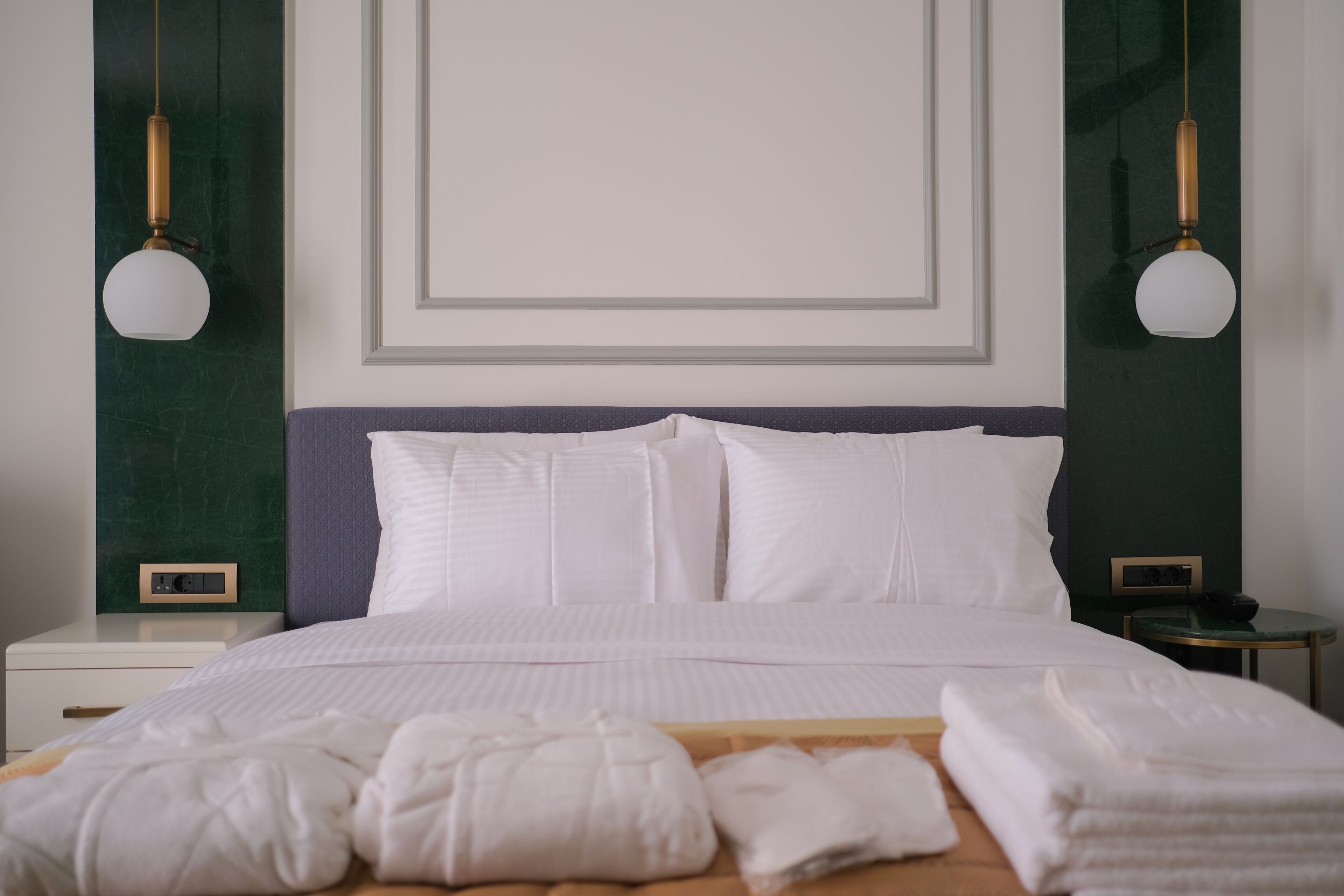 A neatly made bed with white linens, a wooden headboard, and two bedside tables with lamps.